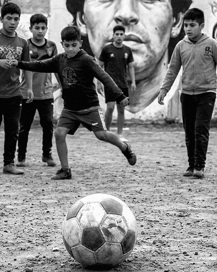 Chicos jugando al fútbol en un potrero